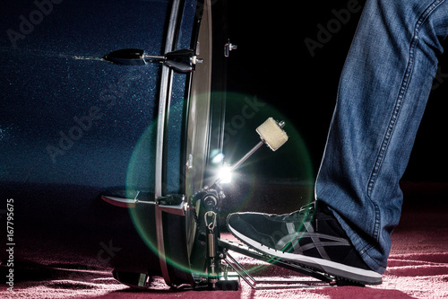 The drummer's foot wears sneaker is playing bass drum pedal