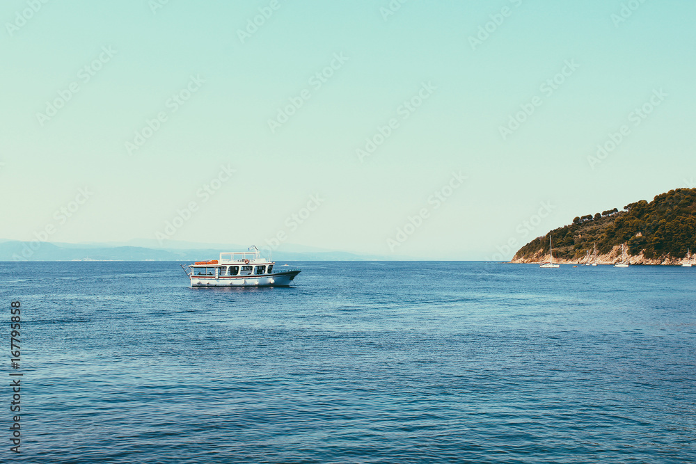 Small cruise ships at the sea near the Greek Islands. Calm sea and blue sky background.