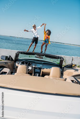 african american couple holding hands while standing on parapet at seaside © LIGHTFIELD STUDIOS