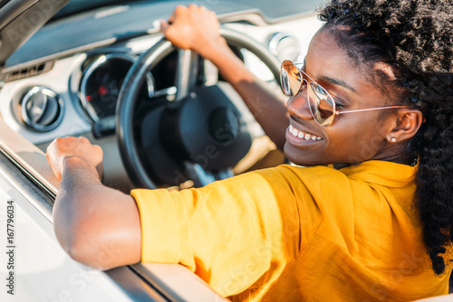 portrait of smiling african american woman in sunglasses riding car