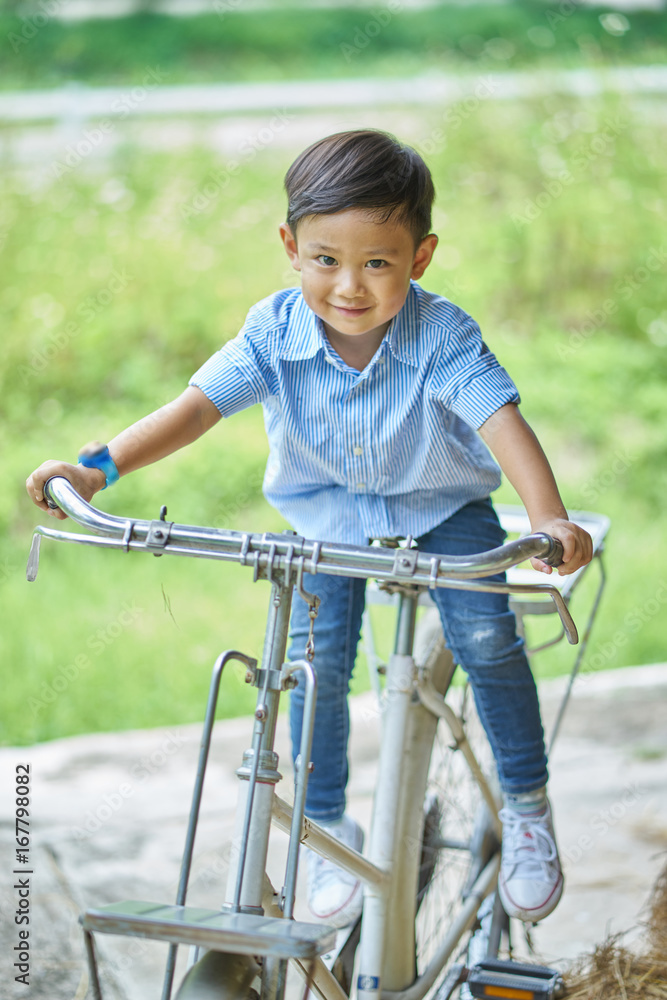 Asian boy sitting on an ancient bicycle. Asian boy sitting on an ancient bicycle.