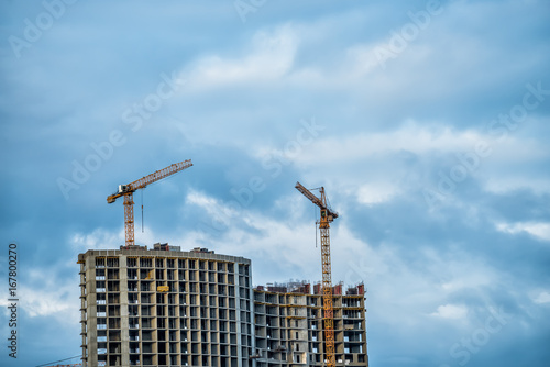 Unfinished high-rise buildings and cranes against the sky
