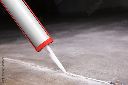 A person will seize a crack with silicone and sealant  photo