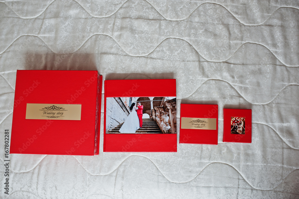 Obraz premium Elegant red wedding photobooks or photo albums with golden inscription on the soft pastel background.
