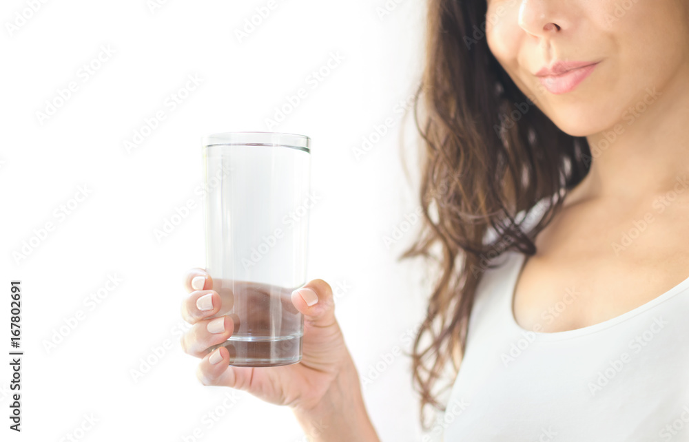 Young smiling woman in white clothes holds a glass of water in her hand. White background. Copy Space Young smiling woman in white clothes holds a glass of water in her hand. White background. Copy Space