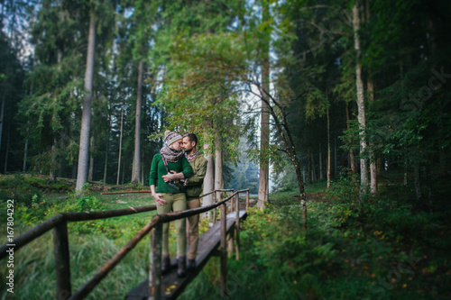 Romantic newlywed couple hugging and kissing in forest