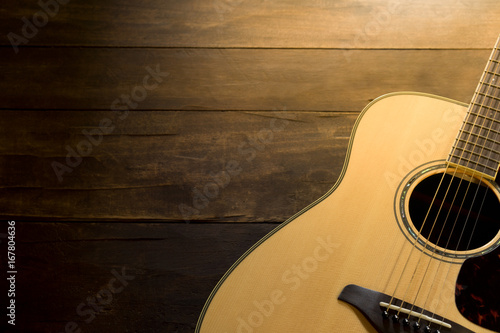 Acoustic guitar resting against a wooden background
