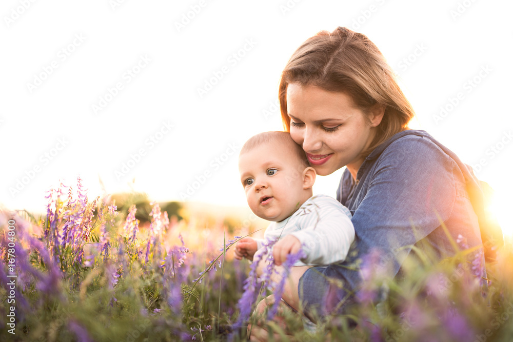 Young mother in nature with baby son in the arms.