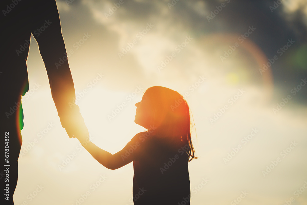 silhouette of little girl holding parent hand at sunset - obrazy, fototapety, plakaty 