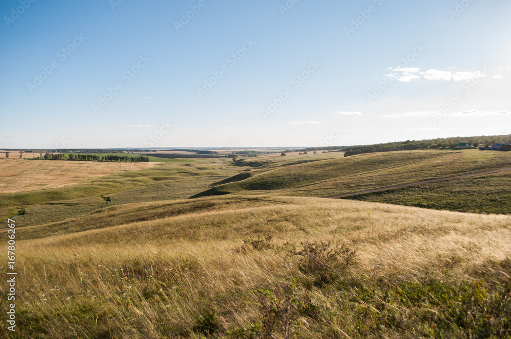 hills, green meadows on the background of blue sky, horizon