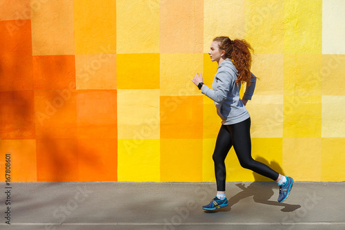 Side view of woman running against bright wall