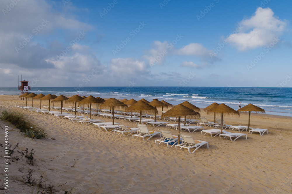 Straw umbrellas on the beach of Barrosa de Sancti Petri, Chiclana, Cadiz, Spain