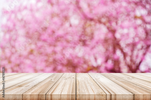 Empty wooden table top with blurred pink cherry or cherry blossom background.