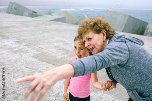 Senior sportswoman pointing while little girl is surprised