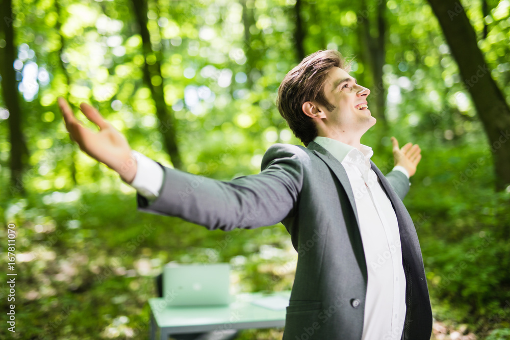 businessman with his arms wide open in green park in front of his office. Business concept businessman with his arms wide open in green park in front of his office. Business concept