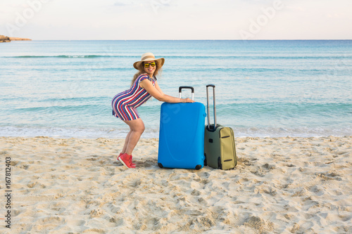 Beautiful young lady with a blue suitcase on the beach. People  travel  vacation and summer concept