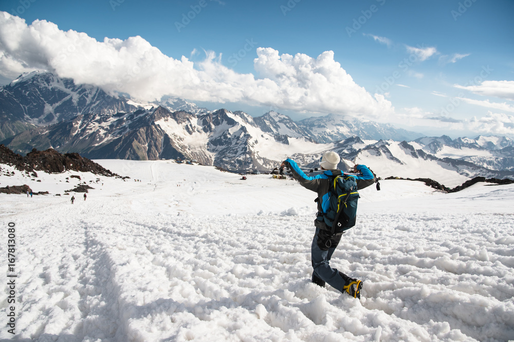 The tired traveler descends from the snowy top against the background of snow-capped mountains