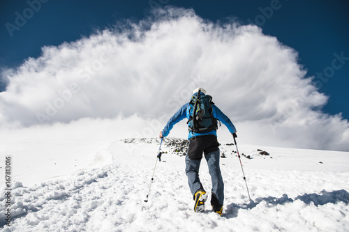 Mountaineer rises uphill to meet a mountain storm coming from the mountain