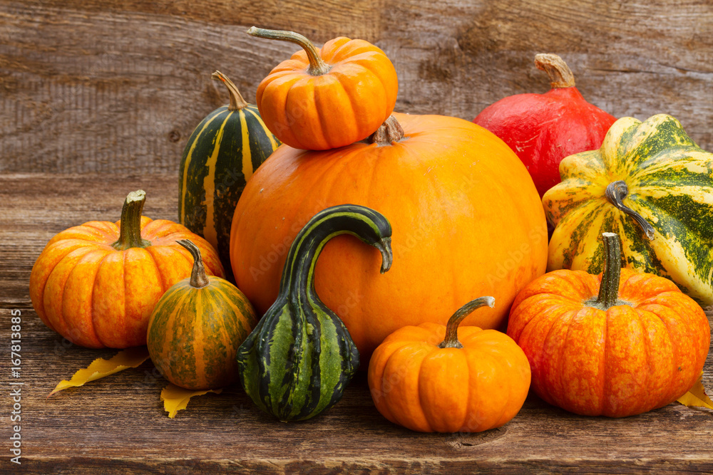 harvest of orange and green pumpkins with fall leaves on wooden table harvest of orange and green pumpkins with fall leaves on wooden table