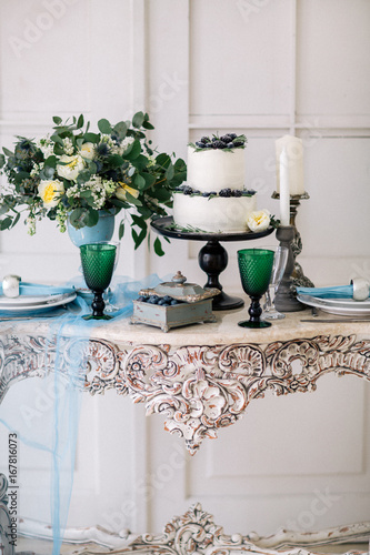beautiful decorate table with candles, vase with flowers and wedding cake on the table in studio