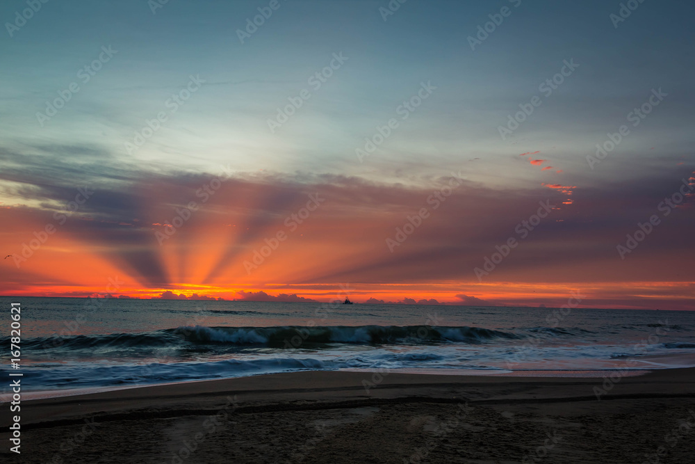 beautiful god ray of sun breaking through clouds at sunrise over the ocean  