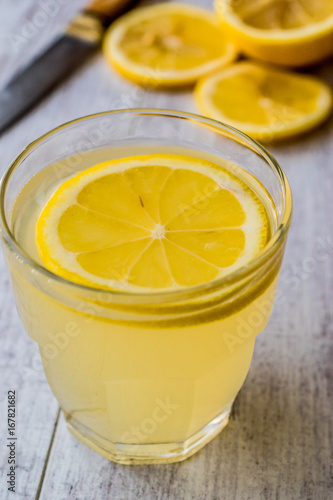 Lemon Liqueur Limoncello with lemon on white wooden surface.