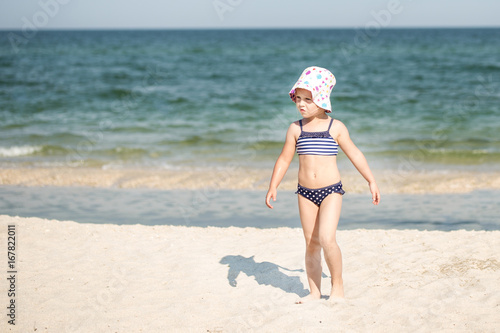 Little cute blonde girl running along the beach