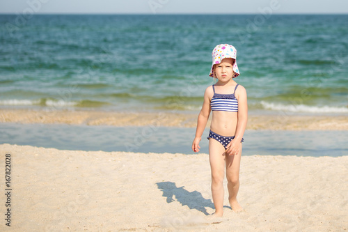 Little cute blonde girl walking away from sea