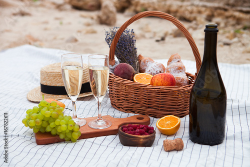 Two glasses of champagne. Picnic on the beach at sunset in the white plaid, food and drink conception photo