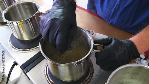 Worker stirs cannabis oil on stove