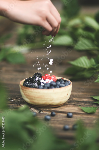 Hand sprinkling powdered sugar over fresh berries