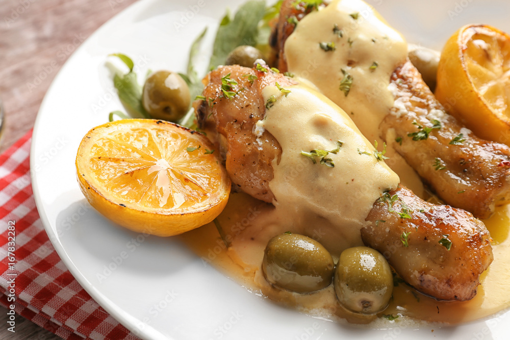 Delicious chicken legs with lemon on plate, closeup