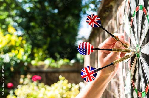 Female hand holding British and American themed darts. Photo can be used to illustrate Anglo-American bonds, themes and concepts