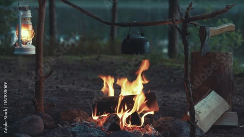idyllic camp setup with tea pot over open fire and hanging kerosene lantern