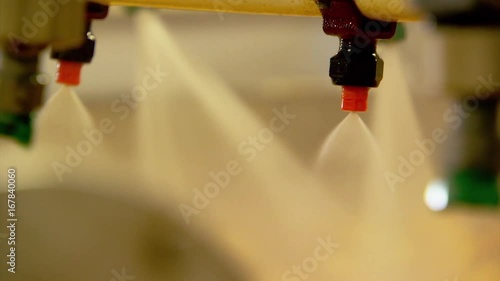 Close up, nozzles spray potatoes with water
