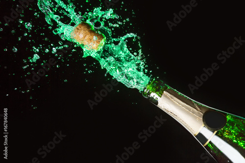 Celebration alcohol theme with explosion of splashing green absinth on black background.