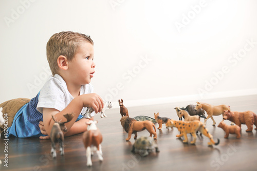 Lifestyle of little boy playing with animal action figures