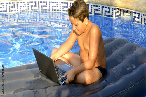 Valokuva El niño esta el la piscina con su ordenador personal