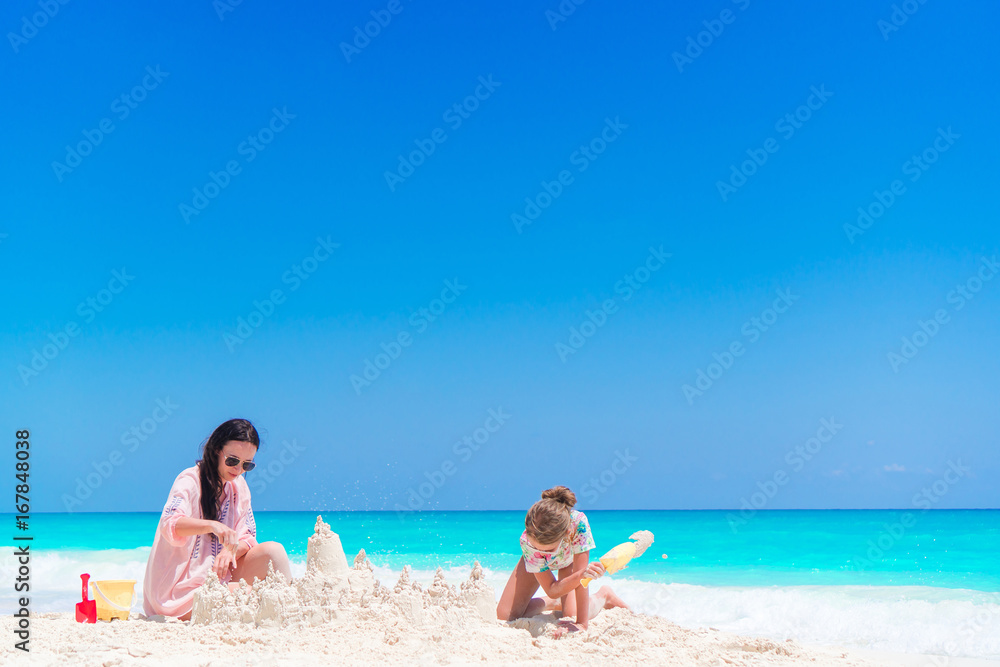 Mother and little kid making sand castle at tropical beach Mother and little kid making sand castle at tropical beach