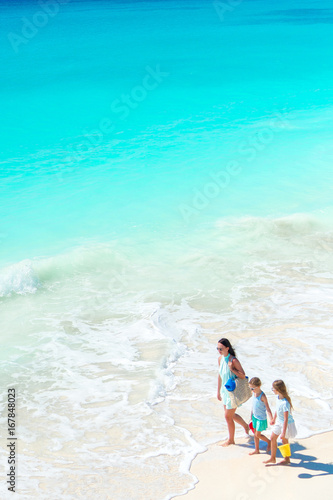 Fototapeta Naklejka Na Ścianę i Meble -  Adorable little girls and young mother on white beach. View to the family on the beach and ocean from above