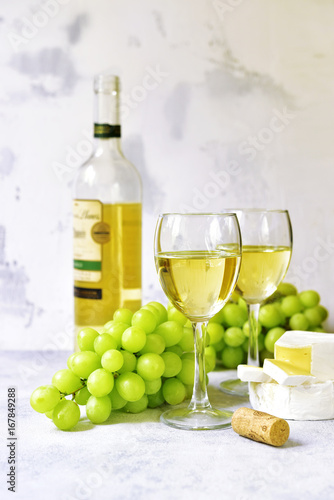 Two glasses of white wine,cheese and grapes.