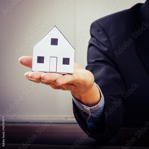 Businessman holding paper home model. Loan concept