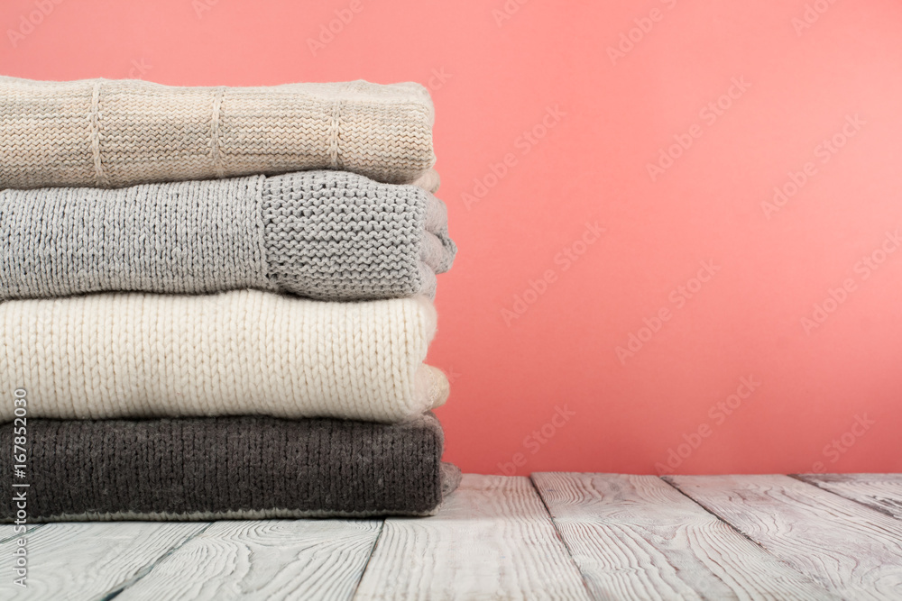 Knitted wool sweaters. Pile of knitted winter, autumn clothes on red, wooden background, sweaters, knitwear, space for text. Knitted wool sweaters. Pile of knitted winter, autumn clothes on red, wooden background, sweaters, knitwear, space for text.