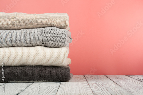 Knitted wool sweaters. Pile of knitted winter, autumn clothes on red, wooden background, sweaters, knitwear, space for text. © lana_u