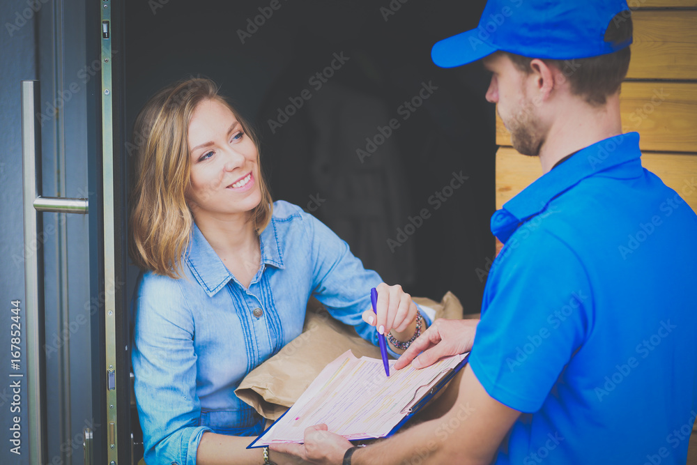 Smiling delivery man in blue uniform delivering parcel box to recipient - courier service concept. Smiling delivery man in blue uniform Smiling delivery man in blue uniform delivering parcel box to recipient - courier service concept. Smiling delivery man in blue uniform