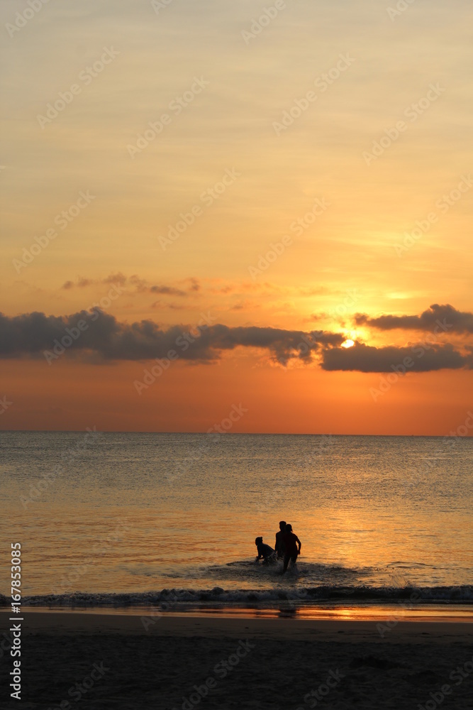 Badende Menschen im Meer vor Sonnenuntergang