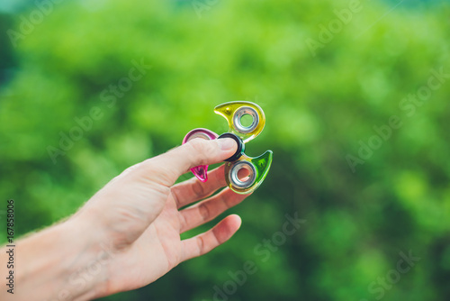 Close up of a man's hand who is holding a fidget spinner in a park photo