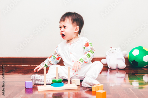 Baby boy sitting with toys and crying