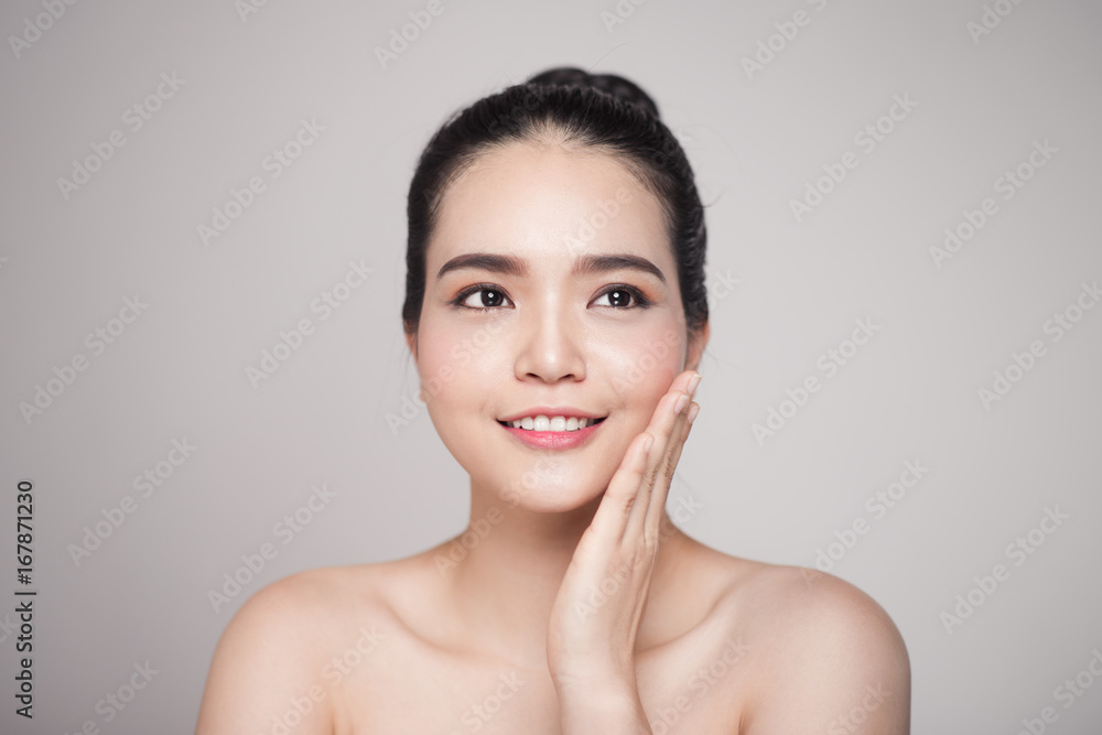 Happy smiling beautiful asian woman touching her face.
