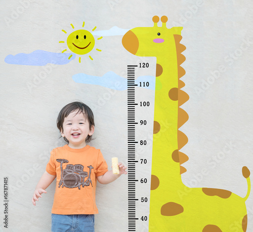 Photography Closeup happy asian kid stand for measure height with cute cartoon at the marble